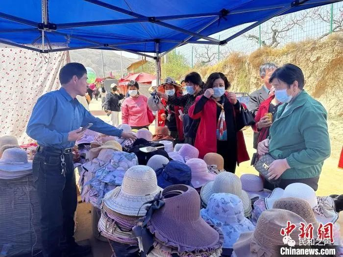 图为游客在桃花林外的小摊上购买凉帽。 李隽 摄 图片